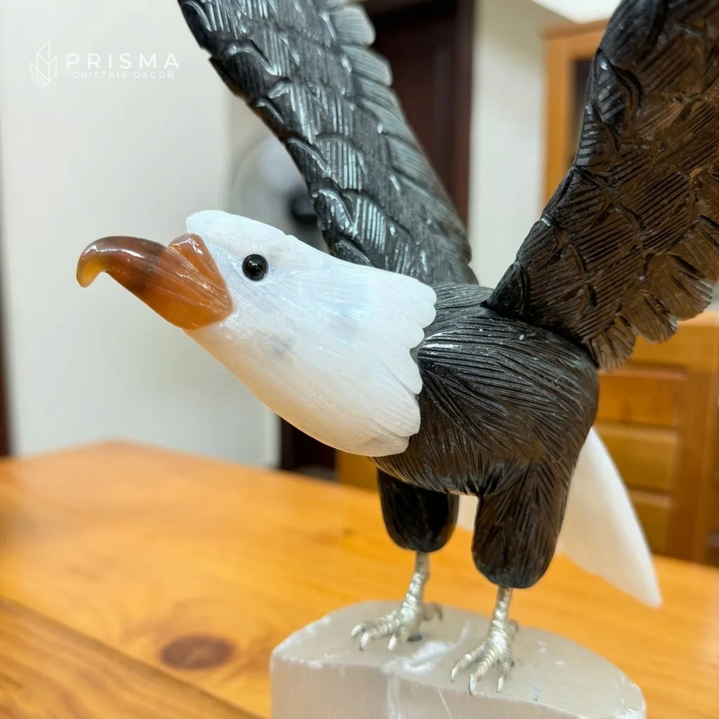 Close da cabeça da escultura de águia em calcita branca com bico em ágata natural e penas em dolomita preta — detalhe artesanal mineral