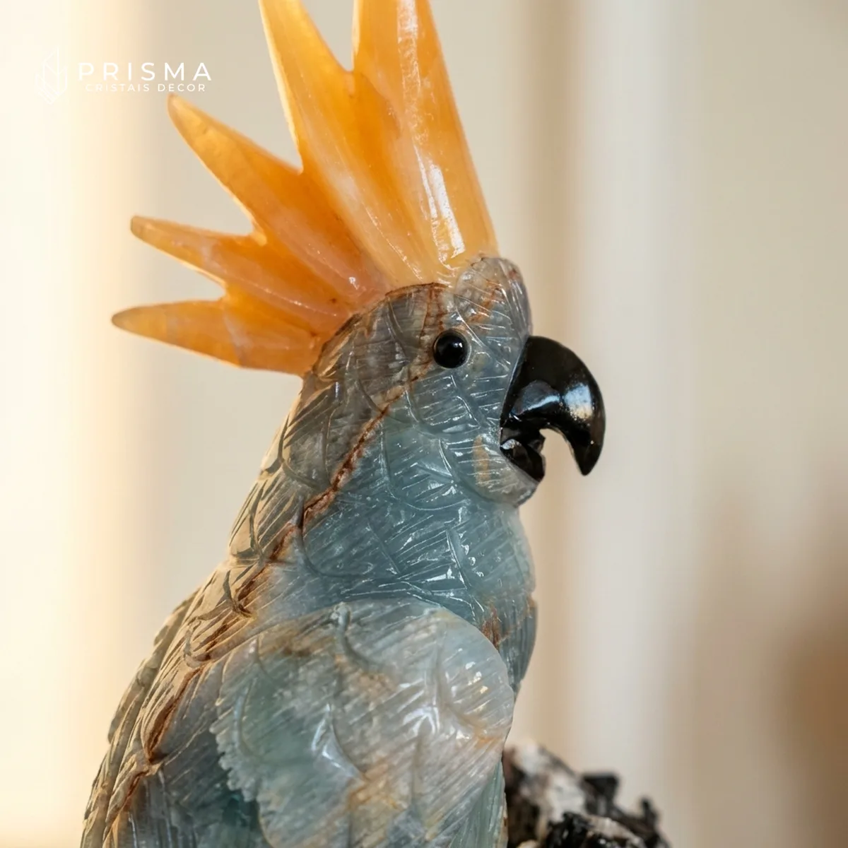 Close nos veios naturais do Ônix Azul e detalhe da crista laranja da cacatua — artesanato mineral de padrão joalheiro