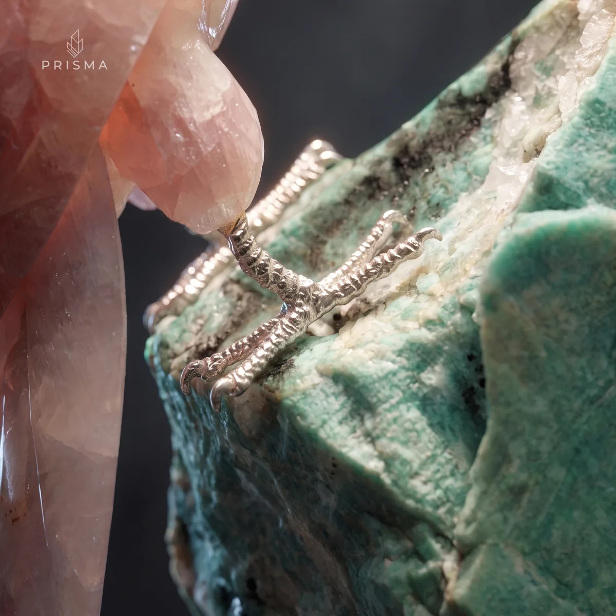 Garras de metal da arara presas ao bloco bruto de amazonita verde-azulada com estrias claras